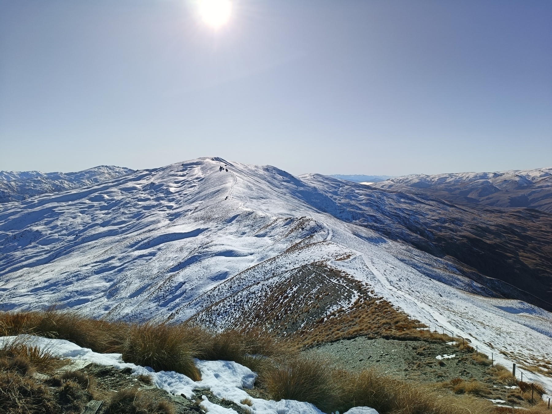 A long snow covered range showing the farm tracks underneath. Clear blue skies.